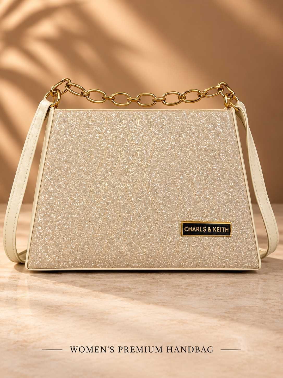 Women's champagne gold glitter party handbag with gold-tone chain handle, cream shoulder strap and trapezoid shape