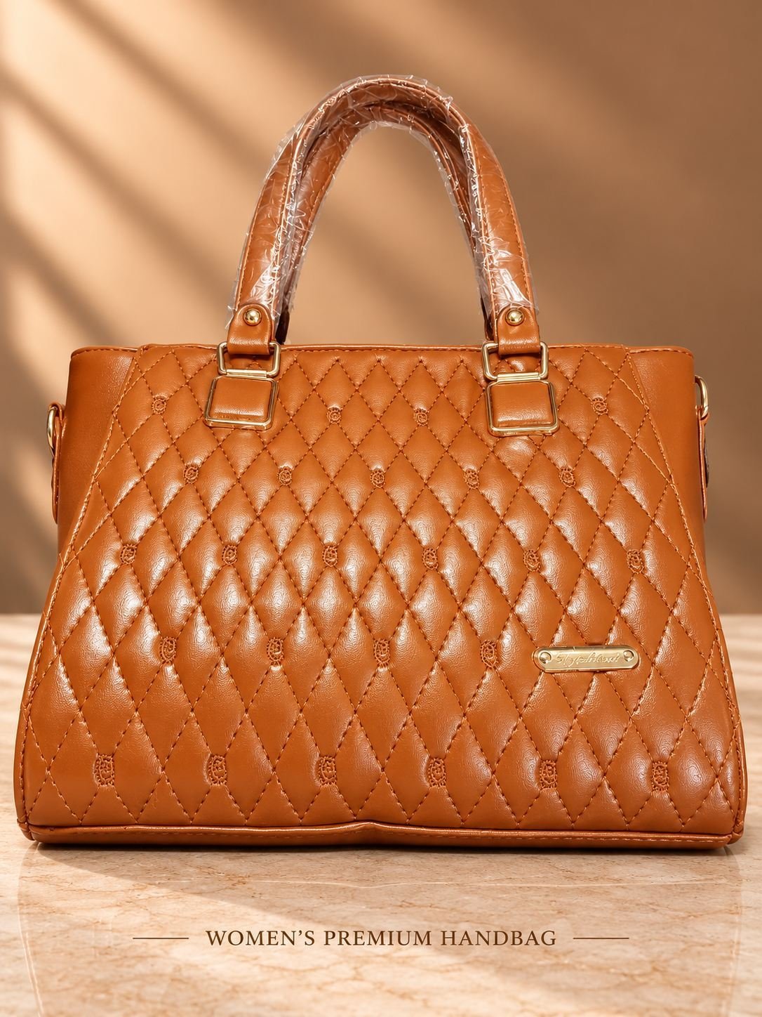 Women's tan brown diamond-quilted handbag with embroidered motifs, two top handles, gold-tone hardware and front plaque